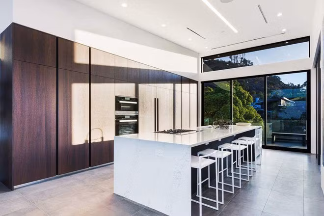 Khu vực bếp núc được thiết kế với vẻ đẹp độc đáo từ chiếc tủ gỗ khổng lồ cùng bộ bàn ghế mang phong cách của các quán bar.