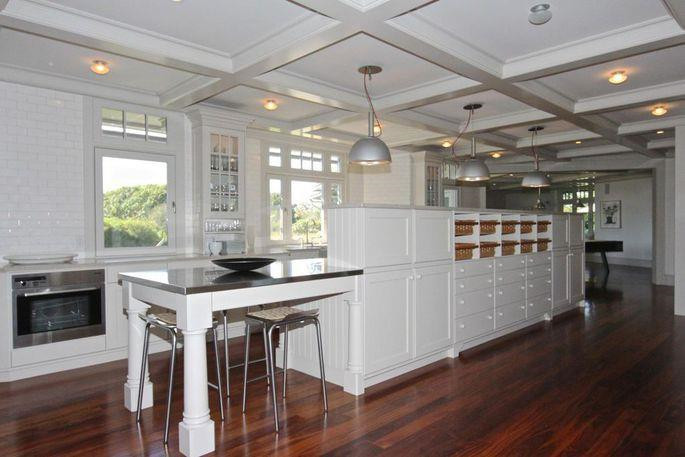 Nhà bếp mang gam màu ấm áp với đèn vàng và sàn gỗ cứng. Những trang thiết bị nấu nướng hiện đại, cao cấp được tích hợp trong các tủ gỗ to lớn và tương đối cồng kềnh.