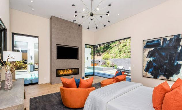 Phòng ngủ chính vừa có sự ấm áp từ lò sưởi và những gam màu sặc sỡ của nội thất, vừa có sự thoáng mát khi được kết hợp với không gian sống ngoài trời.