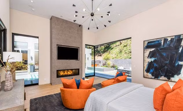 Phòng ngủ chính vừa có sự ấm áp từ lò sưởi và những gam màu sặc sỡ của nội thất, vừa có sự thoáng mát khi được kết hợp với không gian sống ngoài trời.