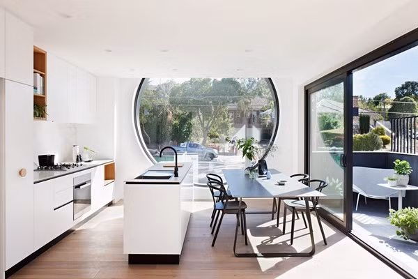 Bên trong nhà, đồ nội thất và tường được sơn màu trắng đối lập với màu xám của gạch bên ngoài. Một cánh cửa trượt lớn được lắp đặt mở ra khu vực ban công với bàn ghế được thiết kế như nơi sinh hoạt ngoài trời cho người cư ngụ.