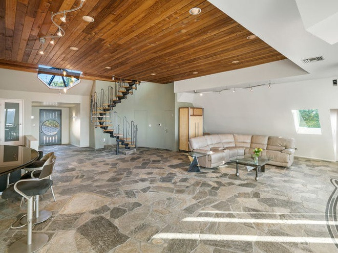 Phòng khách rộng lớn, thoáng đãng, mang phong cách cởi mở, và được chia thành nhiều khu vực khác nhau. Sàn đá độc đáo tạo điểm nhấn cho căn phòng.