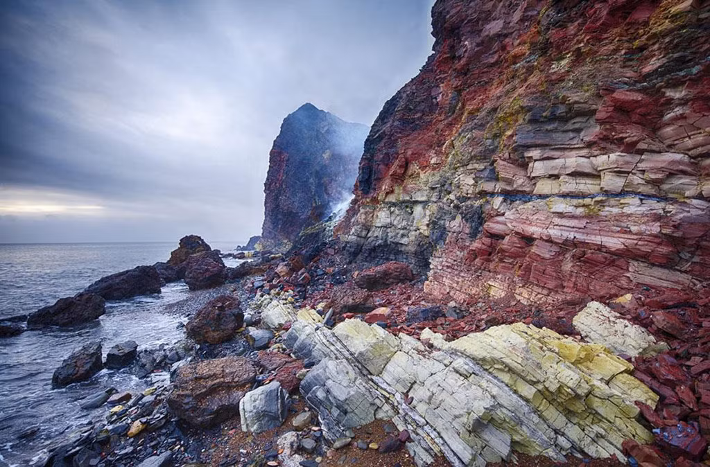 Trong những năm qua, khí SO2 (lưu huỳnh đioxit) từ quá trình đốt cháy đã làm thay đổi độ axit của ngọn đồi đến mức hệ sinh thái ở đây bị biến đổi. Đá và bùn đen được nung dưới sức nóng chuyển sang màu sọc đỏ và cam rực rỡ trên những vách đá, ẩn hiện giữa màn khói mờ ảo. Ảnh: Istockphoto.