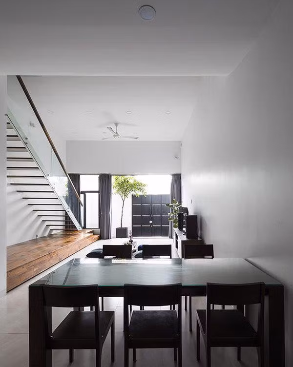 Tầng 1 được bố trí làm chỗ để xe, phòng khách, bếp và bàn ăn. Các khu vực chức năng này không có vách ngăn mà phân chia theo độ cao của trần nhà.