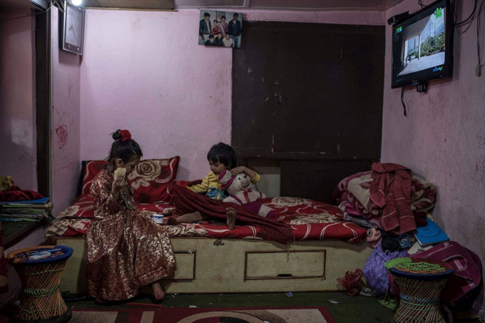 Một nữ thần mới phong của Patan đang ăn sáng với chị hoặc em mình. “Các em 3-6 tuổi khi được chọn và đến từ cộng đồng Newar, người bản xứ ở thung lũng Kathmandu. Kumari chỉ ở trong đền, chỉ có thể nói chuyện với họ hàng và một giáo viên riêng, và không được phép chạm chân xuống đất”, bà Contreras Coll nói với Washington Post. Ảnh: Maria Contreras Coll.