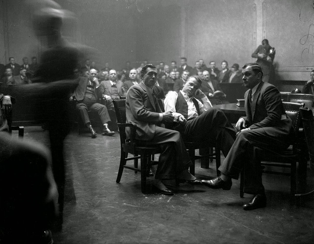 John Dillinger, kẻ cướp 24 ngân hàng Mỹ trong thập niên 1930, bị còng tay trong phiên tòa xét xử tội giết người tại Crown Point, Indiana, Mỹ, tháng 2/1934.