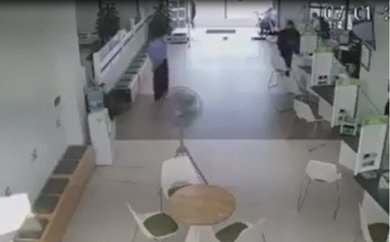 Tên cướp dùng súng uy hiếp bảo vệ ngân hàng.