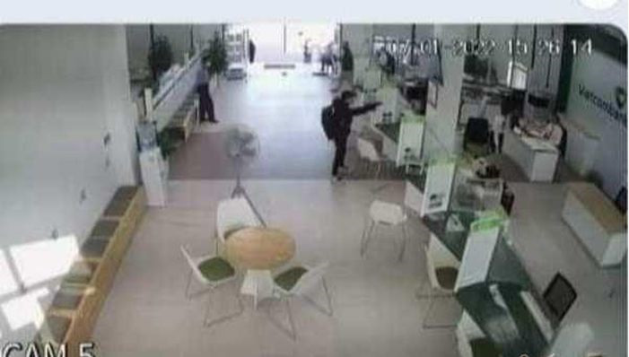 Bị uy hiếp, nhân viên ngân hàng tại quầy giao dịch sợ hãi đưa các cọc tiền cho người mặc áo đen. Người này bình thản nhận và nhét vào trong ba lô.