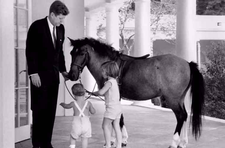 Hai con nhỏ của Tổng thống John F.Kennedy đứng bên ngoài Phòng Bầu dục cùng chú ngựa con năm 1962.