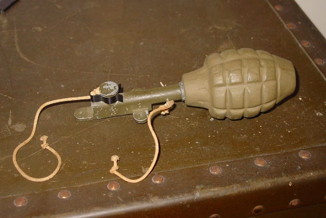 Một loại bẫy được chế lại từ quả lựu đạn với một dây buộc cố định, một dây để rút chốt. Binh lính Mỹ ít có cơ hội được sử dụng đến các loại bẫy mìn vì họ ở thế tấn công, quân Đức ở thế rút lui có cơ hội sử dụng bẫy nhiều hơn do họ có thời gian để cài bẫy ở nơi mình đóng quân trước khi bị quân Đồng Minh chiếm mất. Nguồn ảnh: Militaria.