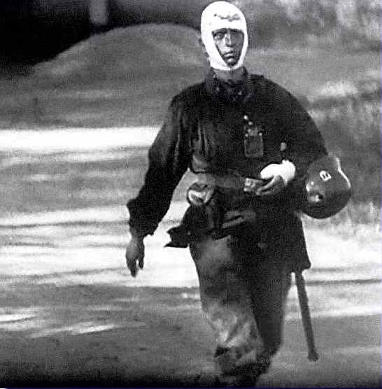 Một thương binh Đức đầu quấn đầy băng trắng ở trên đầu và bàn tay trái. Chiếc mũ sắt của người lính này có một vết lõm khá sâu, có lẽ nó đã đỡ cho anh một viên đạn. Nguồn ảnh: Histomil.