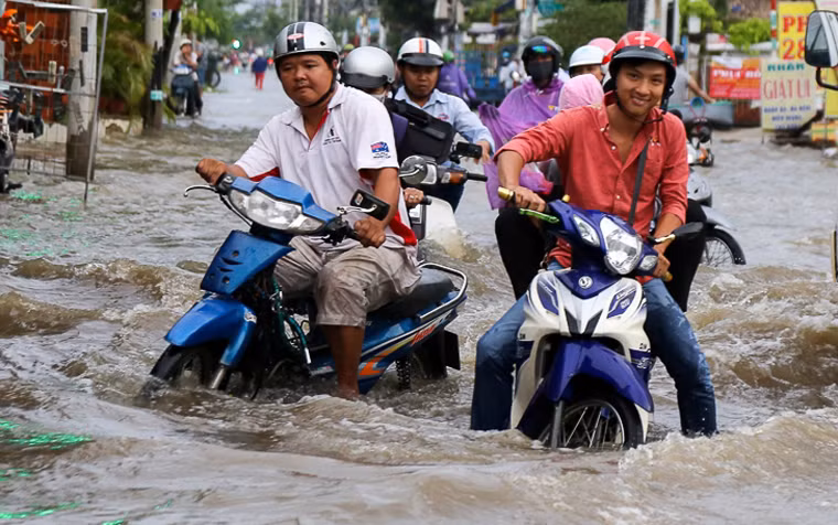 Người đi xe máy chới với giữa dòng nước trên đường phố ở TP.HCM.