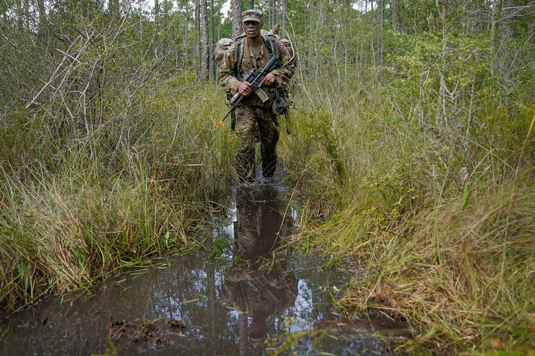 Trung sỹ Warren Jenskins đi tuần tra qua một đầm lầy.