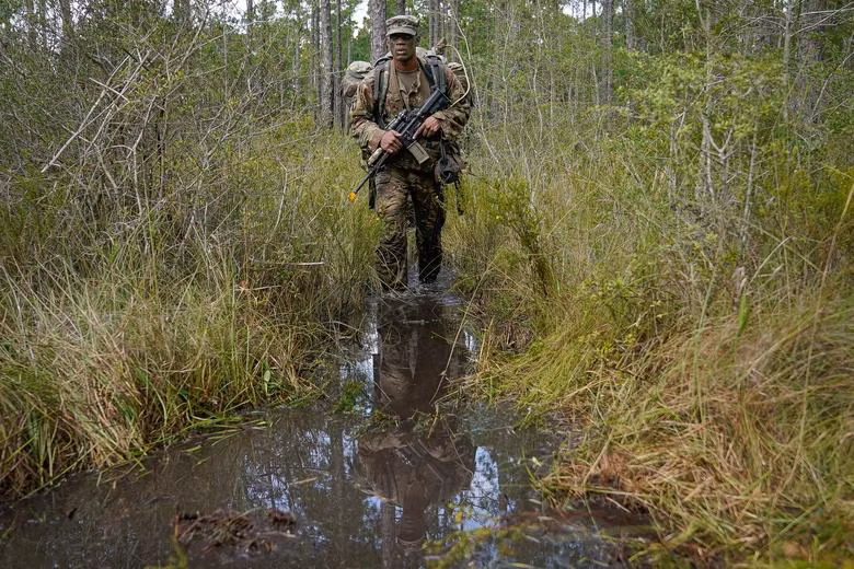 Trung sỹ Warren Jenskins đi tuần tra qua một đầm lầy.