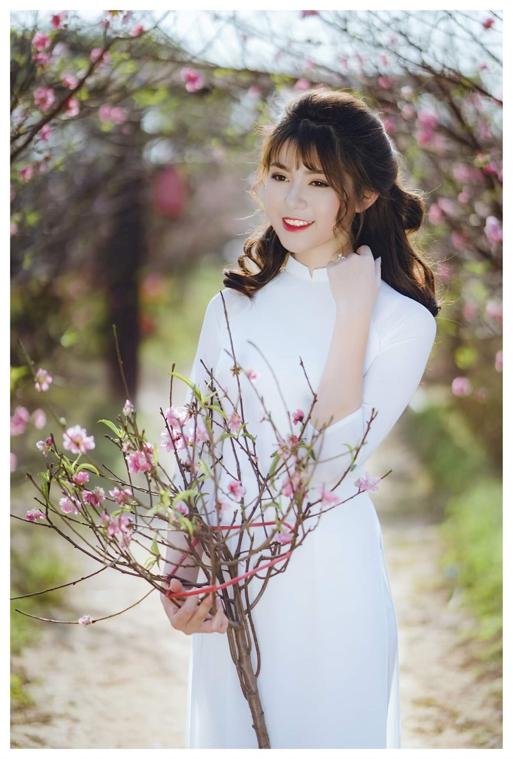 Nữ sinh 10x diện áo dài trắng tinh khôi , hòa với sắc hồng của vườn đào tạo nên những bức ảnh hài hòa như tranh vẽ.