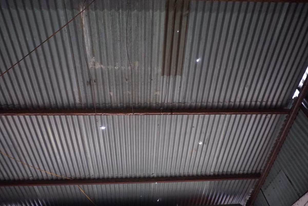 Mái tôn thủng lỗ chỗ vì những viên đạn bắn ra từ vụ nổ.