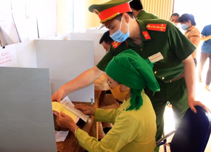 Cán bộ chiến sỹ Công an huyện Tân Uyên hướng dẫn người dân cách thức viết phiếu bầu. (Ảnh Thu Trang/ Báo Lai Châu)