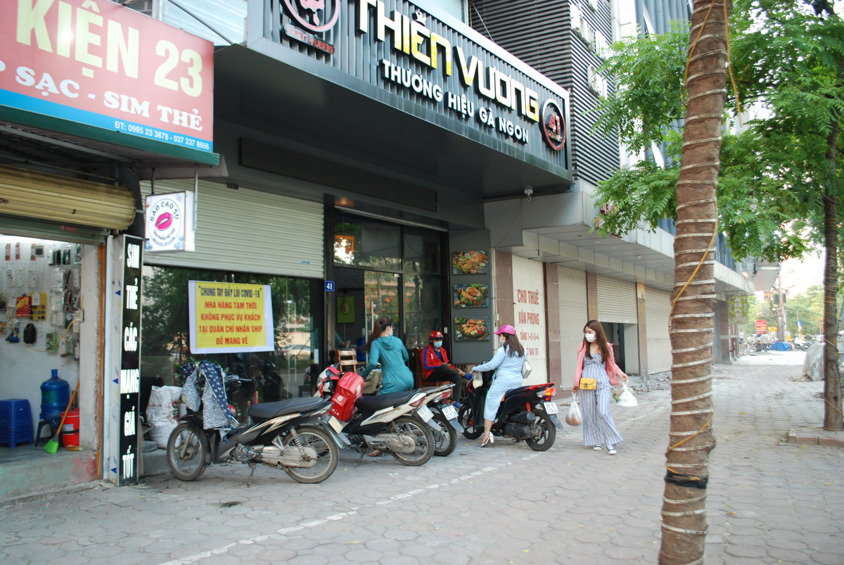 Các hàng quán trên đường Nguyễn Hoàng đồng loạt treo biển "Chỉ bán mang về". Những ô cửa khép lại tạm dừng hoạt động buôn bán tại chỗ. Nhiều cửa hàng đã chuẩn bị sẵn đồ ăn theo từng túi để khách tiện mang đi.