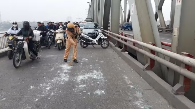 Cán bộ Đội CSGT số 5, Phòng CSGT Công an Hà Nội quét dọn kính vỡ trên cầu Chương Dương.