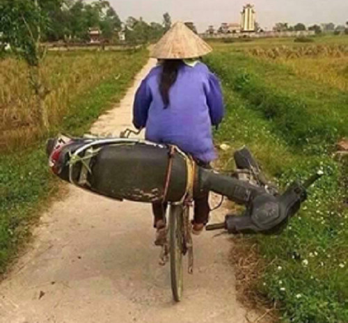 Xe đạp chở xe máy trên đường làng.