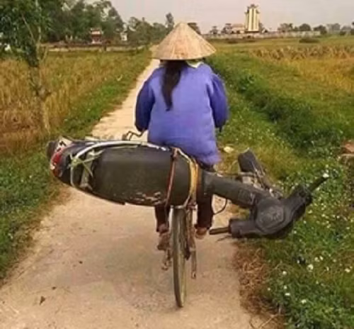 Xe đạp chở xe máy trên đường làng.