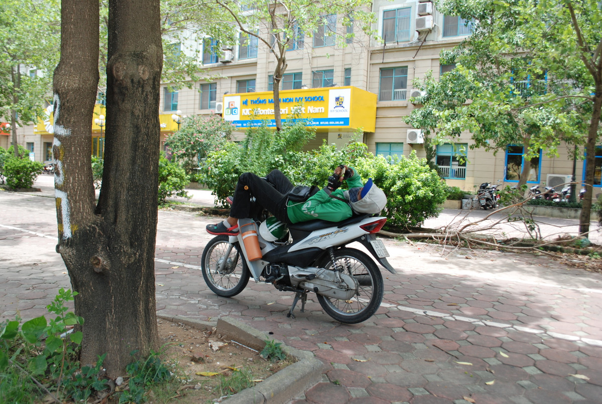 Phút nghỉ ngơi của tài xế xe ôm công nghệ tại phố Mễ Trì, Nam Từ Liêm, (Hà Nội).