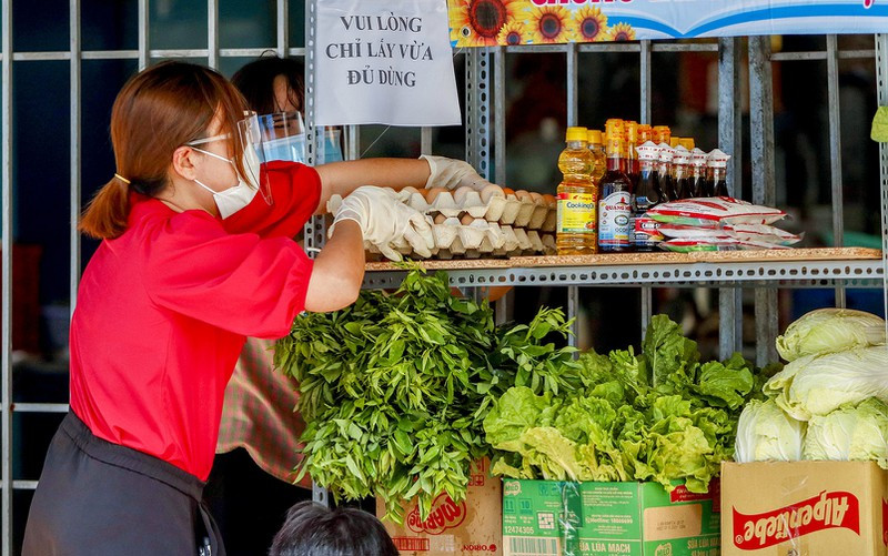 Chị Vũ Xuân Quỳnh (UBMTTQ phường Tân Quý) mang từng túi chứa rau củ, vận chuyển vào khu vực gian hàng. Chị Quỳnh cho biết, mỗi ngày từ 6 giờ sáng chị cùng những người trong ban tổ chức đến chợ Tân Hương để mua và nhận rau củ được tặng từ các tiểu thương sau đó mang về hẻm 17, đường Gò Dầu.