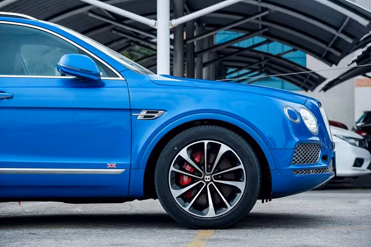 Ngay khi mở cửa xe, logo chữ B cùng viền vàng Centenary Gold sẽ phản chiếu dưới mặt đường, bên cạnh đó là 2 con số 1929-2019 được khắc trên bậc cửa xe. Chưa hết, chiếc SUV siêu sang Bentley Bentayga V8 mang màu xanh Neptune độc nhất vô nhị tại Việt Nam còn có thêm trang bị Cờ Liên hiệp Anh xuất hiện bên hông xe.