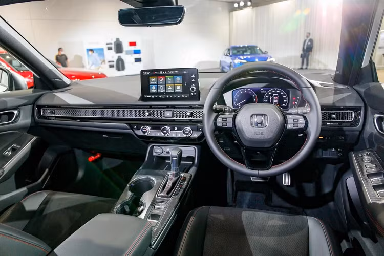 Bên cạnh đó là bảng đồng hồ kỹ thuật số với màn hình 10,2 inch và tấm lưới phủ lên cửa gió điều hòa kéo dài trên mặt táp-lô. Cửa sổ bên sườn cỡ lớn hơn mang đến cảm giác thoáng đãng hơn cho không gian nội thất. Ngoài ra, khoảng duỗi chân dành cho hành khách ngồi trên hàng ghế sau của Honda Civic Hatchback 2022 còn được tăng 35 mm so với thế hệ cũ.