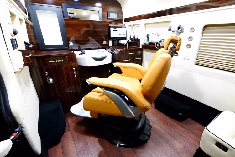 Cụ thể hơn, nội thất xe sử dụng nhiều chất liệu bọc màu trắng thiết kế riêng với tường ngăn phía trước cách âm, mặt sàn giống như lát gỗ, mặt bàn nhiều lớp bằng gỗ làm theo yêu cầu, bồn rửa lớn với nước nóng/lạnh, và tất nhiên là chiếc ghế tuyệt đẹp đó cũng ngả và xoay. Nhìn chung, một cửa tiệm cắt tóc thông thường có gì thì cửa tiệm cắt tóc di động này có đủ thứ đó.