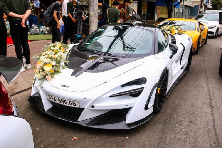 Thu hút nhiều sự chú ý từ người đi đường nhất chính là phiên bản nâng cấp McLaren 720S Novitec N-Largo vừa được chủ nhân "tậu" về garage cách đây chưa lâu. Nhằm phục vụ cho ngày trọng đại, diện mạo của mẫu siêu xe Anh Quốc đã được trang trí với các dải hoa hồng đẹp mắt. Lớp sơn tím MSO Lantana Purple nguyên bản đã được dán decal chuyển sang tông màu trắng trang nhã.