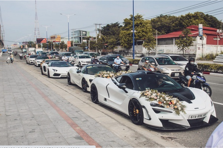 Di chuyển phía sau là một chiếc 720S khác được dán decal màu trắng và "siêu bò" Lamborghini Aventador Roadster LP700-4 độ ống xả Novitec. Tiếp đến là mẫu siêu xe mui trần đến từ nước Ý Ferrari F8 Spider. Tương tự chiếc 720S của chú rể, "siêu ngựa" với lớp sơn vàng Giallo Modena này cũng được nâng cấp với một bộ bodykit từ Novitec.