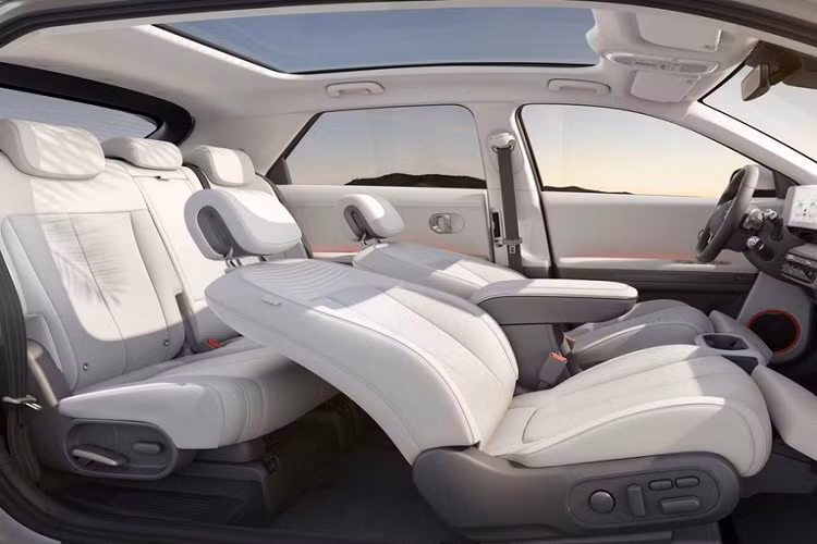 Chưa hết, Hyundai Ioniq 5 còn có cần số nằm sau vô lăng và màn hình hiển thị thông tin kính lái, hỗ trợ công nghệ thực tế ảo. Thêm vào đó là cụm điều khiển trung tâm của hàng ghế trước có thể trượt lên/xuống trong khoảng cách 140 mm. Trang bị này sẽ tiện dụng trong những bãi đỗ xe chật hẹp. Lúc đó, tài xế có thể trượt cụm điều khiển trung tâm về phía sau rồi ra khỏi xe thông qua cửa bên ghế phụ lái và ngược lại.