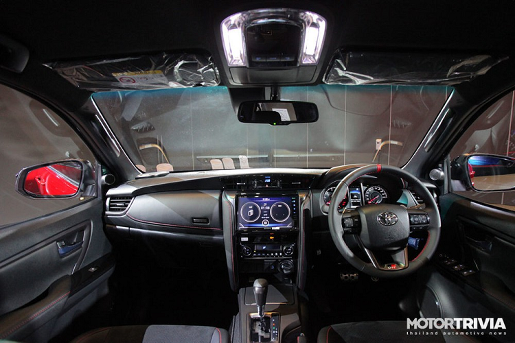 Bên trong Toyota Fortuner GR Sport dành cho thị trường Thái Lan là không gian nội thất màu đen chủ đạo, có thêm chỉ khâu màu đỏ làm điểm nhấn tương phản. Ghế trước của xe được bọc da phối da lộn và có logo "GR Sport" trên tựa đầu.
