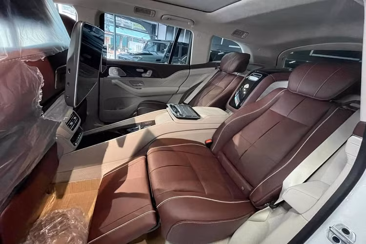 Bên trong Mercedes-Maybach GLS 600 2021 là không gian nội thất 4 chỗ với 2 ghế thương gia phía sau. Không chỉ có khoảng duỗi chân thoải mái, ghế sau của mẫu SUV siêu sang này còn có thể ngả 43,5 độ và đi kèm tính năng nhớ vị trí, sưởi, làm mát cũng như mát-xa tiêu chuẩn. Nằm giữa hàng ghế sau là cụm điều khiển trung tâm, tích hợp cả ngăn chứa đồ có khóa hoặc tủ lạnh nhỏ. Ngoài ra, hành khách phía sau còn tìm thấy hộc đựng cốc có tính năng hâm nóng hoặc làm mát đồ uống trên xe.