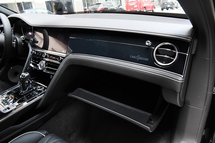 Mở cửa bước vào trong khoang lái, những dấu hiệu đặc biệt của dòng xe Bentley Flying Spur First Edition 2021 sẽ thể hiện ngay lập tức ở bậc cửa với dòng chữ Bentley phát sáng và phía trên còn có dòng chữ First Edition lồng vào trong logo cờ Anh. Ngoài ra Logo hình quốc kỳ Anh với số 1 còn xuất hiện trên bảng táp-lô, trước mặt ghế phụ của xe Bentley Flying Spur First Edition 2021.