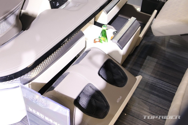 Trên bệ tì tay trung tâm giữa 2 ghế sau có màn hình cảm ứng 7 inch để hành khách chỉnh các tính năng của xe. Để đảm bảo sự riêng tư cho hành khách, hãng Kia đã lắp thêm rèm ở hàng ghế sau. Trong khi đó, hệ thống lọc không khí được tích hợp vào phía sau lưng ghế phụ lái.