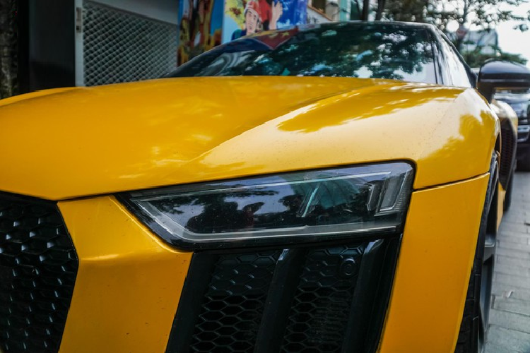 Với cá nhân chiếc Audi R8 V10 Plus trong bài viết, xe được trang bị bộ mâm năm chấu kép sơn đen khá hầm hố, ẩn bên trong là đĩa phanh carbon ceramic kết hợp với cùm phanh sơn vàng tương tự lớp sơn ngoại thất. Di chuyển ra phía sau, phần đuôi xe có thiết kế khá tương đồng phần đầu với khe hút gió sơn đen cùng các lưới dạng tổ ong được đặt gọn gàng ngay bên dưới cụm đèn hậu dạng Led. Cặp ống xả kép cùng các cánh gió gầm xe càng làm gia tăng vẻ nam tính cho mẫu xe có thiết kế đầy mềm mại này.