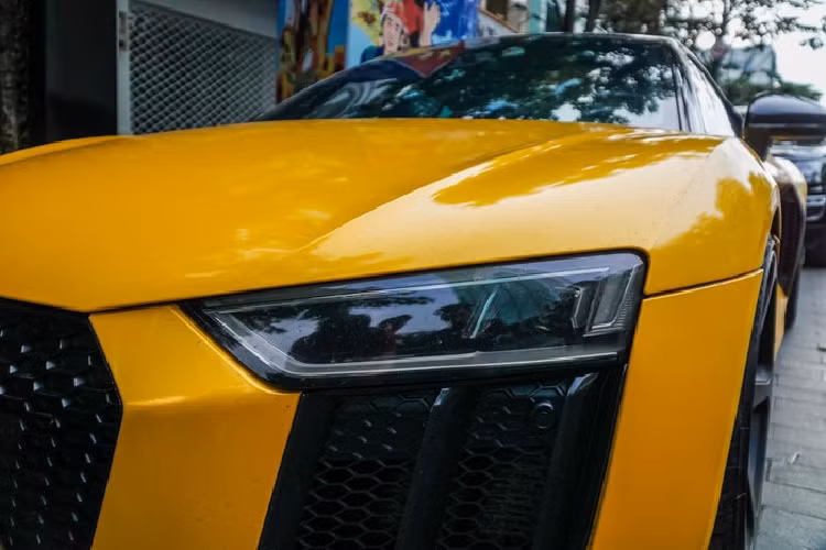 Với cá nhân chiếc Audi R8 V10 Plus trong bài viết, xe được trang bị bộ mâm năm chấu kép sơn đen khá hầm hố, ẩn bên trong là đĩa phanh carbon ceramic kết hợp với cùm phanh sơn vàng tương tự lớp sơn ngoại thất. Di chuyển ra phía sau, phần đuôi xe có thiết kế khá tương đồng phần đầu với khe hút gió sơn đen cùng các lưới dạng tổ ong được đặt gọn gàng ngay bên dưới cụm đèn hậu dạng Led. Cặp ống xả kép cùng các cánh gió gầm xe càng làm gia tăng vẻ nam tính cho mẫu xe có thiết kế đầy mềm mại này.