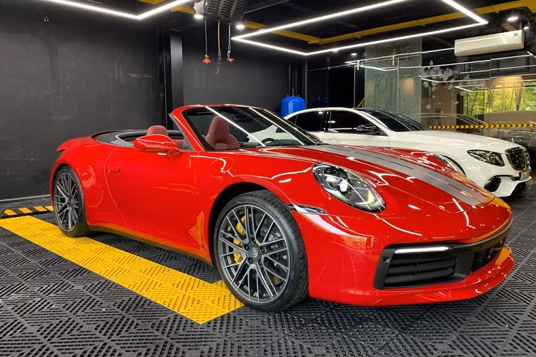 Chiếc xe Porsche 911 Carrera S Cabriolet 2021 của người chơi lan đột biến ở Bình Phước mang ngoại thất màu đỏ rất đẹp mắt, xe có thêm sọc kép màu bạc chạy dài từ nắp capô trước ra phía sau, ngoài ra là bộ mâm đa chấu kép sơn màu bạc. Chưa hết, các trang bị an toàn của xe cũng thuộc diện "hết nấc".