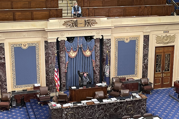 Một người biểu tình ngồi trên bàn chủ tịch trong phòng họp Thượng viện. Ảnh: Matt Fuller/HuffPost 