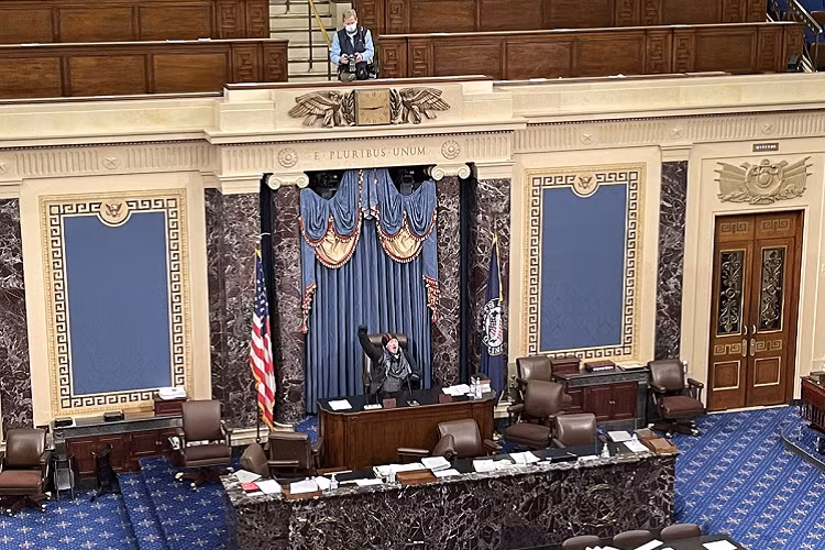 Một người biểu tình ngồi trên bàn chủ tịch trong phòng họp Thượng viện. Ảnh: Matt Fuller/HuffPost 