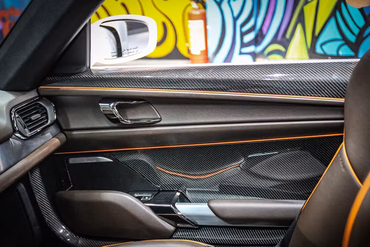 Nội thất của xe được bọc trong da màu nâu, kết hợp với các điểm nhấn màu cam. Vật liệu carbon sử dụng khá nhiều trên ghế, cửa xe, bậc cửa.