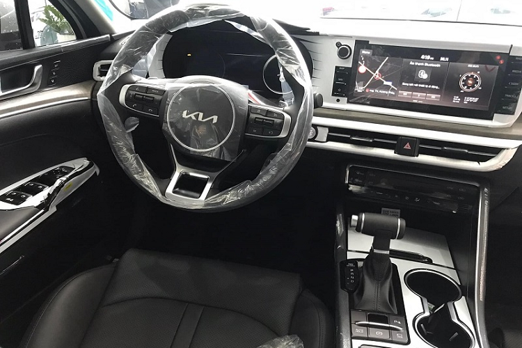 Ở bên trong, Kia K5 GT-Line 2022 mang đến cảm giác thể thao với vô lăng 3 chấu dạng vát đáy, màn hình công cụ kỹ thuật số 12,3 inch nằm phía sau, thiết kế bảng điều khiển trung tâm tập trung về phía người lái,... Toàn bộ khoang cabin của phiên bản GT-Line này được bọc da tông màu đen, ghế lái chỉnh điện đa hướng và tích hợp tính năng sưởi/thông gió.