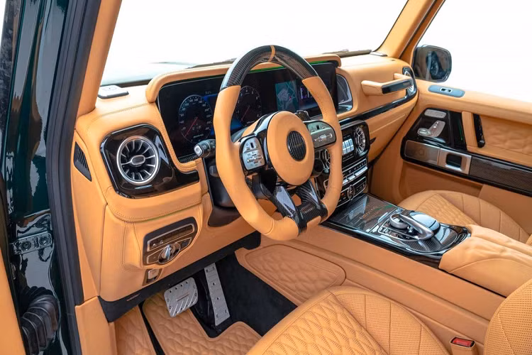 Cabin của Mercedes-AMG G63 Gronos độ Mansory "lột xác" trở nên sang trọng hơn khi vật liệu da phủ gần như kín nội thất. Bảng táp-lô, vô-lăng, bệ tự tay, táp-pi cửa, trần xe hay khoang hành lý đều được bọc da cao cấp màu nâu Fawn Brown. Bên cạnh đó, vật liệu carbon cũng được sử dụng để trang trí ở tay lái, khu vực điều khiển trung tâm..