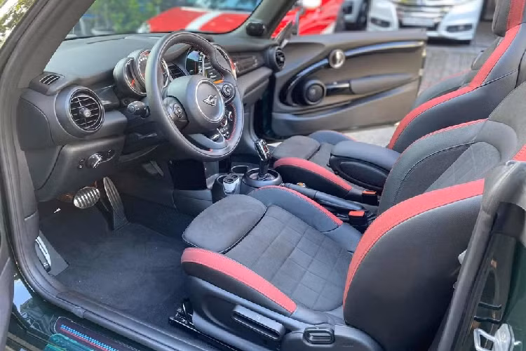 Chưa hết, bên hông mẫu xe mui trần MINI John Cooper Works Convertible này còn có đề-can màu đỏ nổi bật chạy dài hết bên hông xe. Ngoài ra là logo JCW viết tắt từ John Cooper Works đặt trước bánh xe sau.