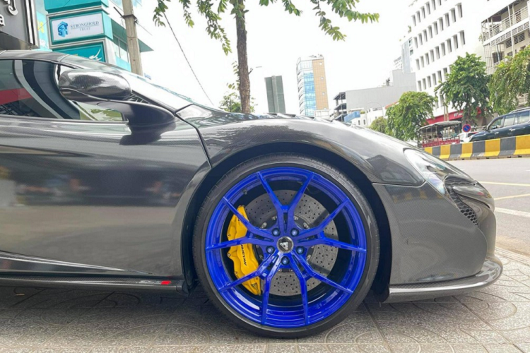 Việc "phủ carbon" cho ngoại thất chiếc xe McLaren 650S Spider đã gây ấn tượng mạnh với giới mê xe. Không chỉ thế, siêu xe mui trần này còn sở hữu bộ la-zăng độ rất nổi bật với tông màu xanh dương cá tính, đối lập bộ áo carbon bằng đề-can. La-zăng độ 5 chấu kép của chiếc McLaren 650S Spider của hãng Vossen với cùm phanh sơn vàng