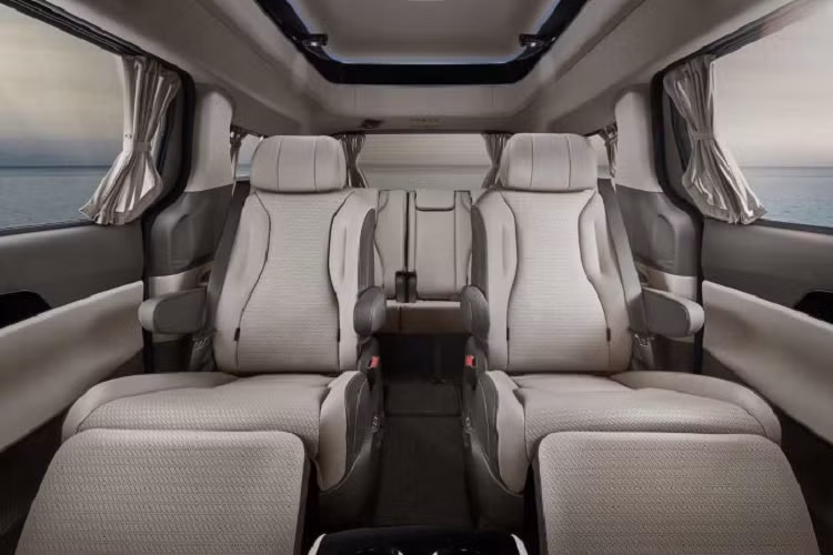 Nằm giữa 2 ghế thương gia phía sau của Kia Carnival High Limousine 2022 là bệ tì tay trung tâm tích hợp màn hình cảm ứng 7 inch. Hành khách có thể dùng màn hình này để chỉnh nhiều tính năng của xe. Thêm vào đó là hộc đựng cốc có tính năng hâm nóng/làm mát đồ uống, sạc điện thoại thông minh không dây, bàn gấp và ngăn chứa đồ mới cho hành khách ngồi trên ghế sau.