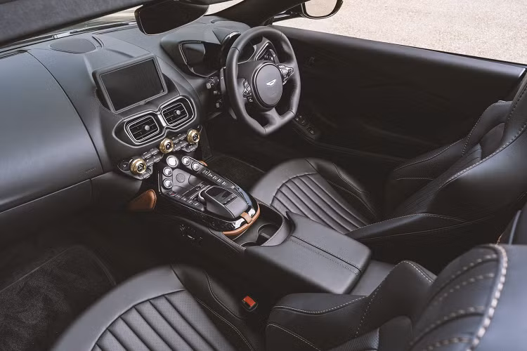 Tương tự ngoại thất, khoang lái của chiếc Vantage Roadster cũng mang màu sắc cổ điển nhờ cách phối màu đơn giản giữa tông đen chủ đạo. Xen lẫn trong đó là các chi tiết màu đồng như nút chỉnh điều hòa, ốp trang trí bệ tựa tay hay chỉ khâu ghế ngồi.
