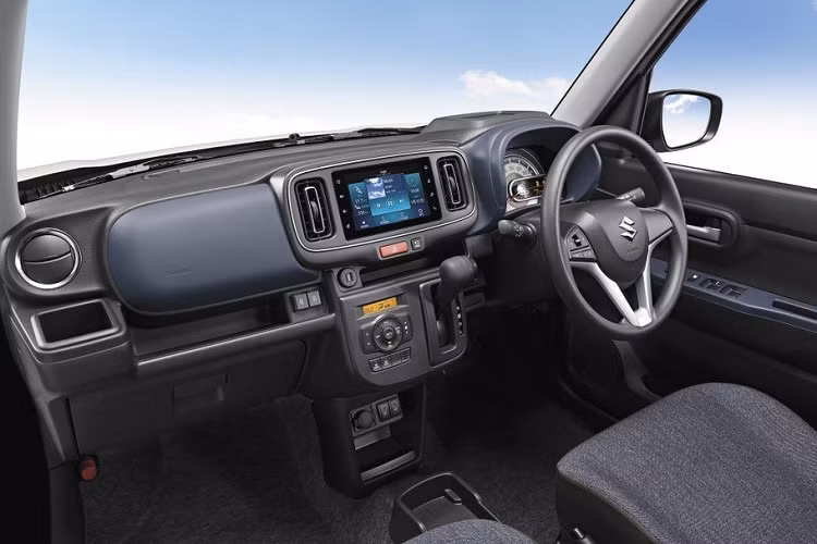 Vì là xe giá rẻ nên Suzuki Alto 2022 chỉ được được trang bị ghế bọc nỉ và không hề có bệ tì tay trung tâm. Bên cạnh đó là vô lăng mới, tích hợp phím chỉnh âm lượng hoặc kết nối Bluetooth. Đằng sau vô lăng, bảng đồng hồ có thêm màn hình LCD nhỏ nằm ngang, tạo cảm giác phức tạp hơn.